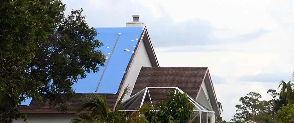 A home with a blue tarp applied over roof damage in Plant City, FL.
