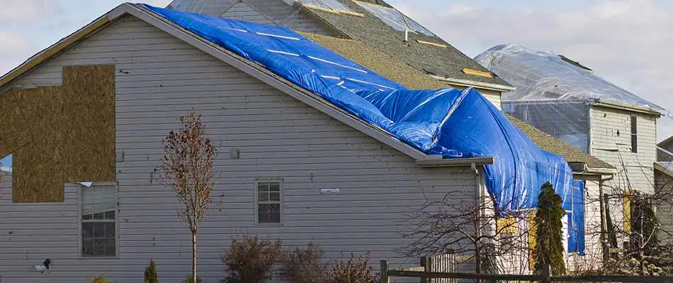 A storm damaged home with a blue tarp covered roof in Winter Haven, FL.