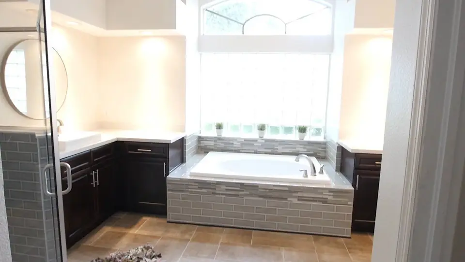 Bathroom remodeling in Tampa FL: a finished True Builders bathroom with a tiled tub surround, glass shower, and new vanities